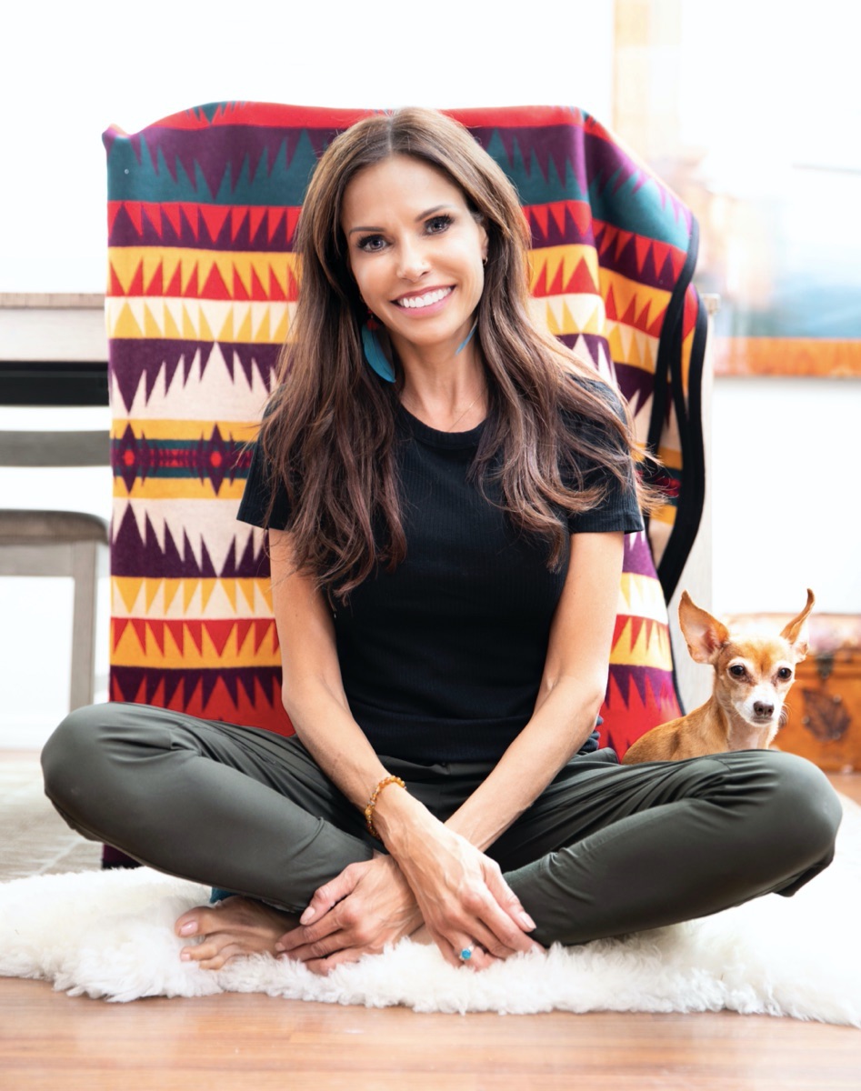 Nadia Davis sitting on the floor with a colorful blanket behind her
